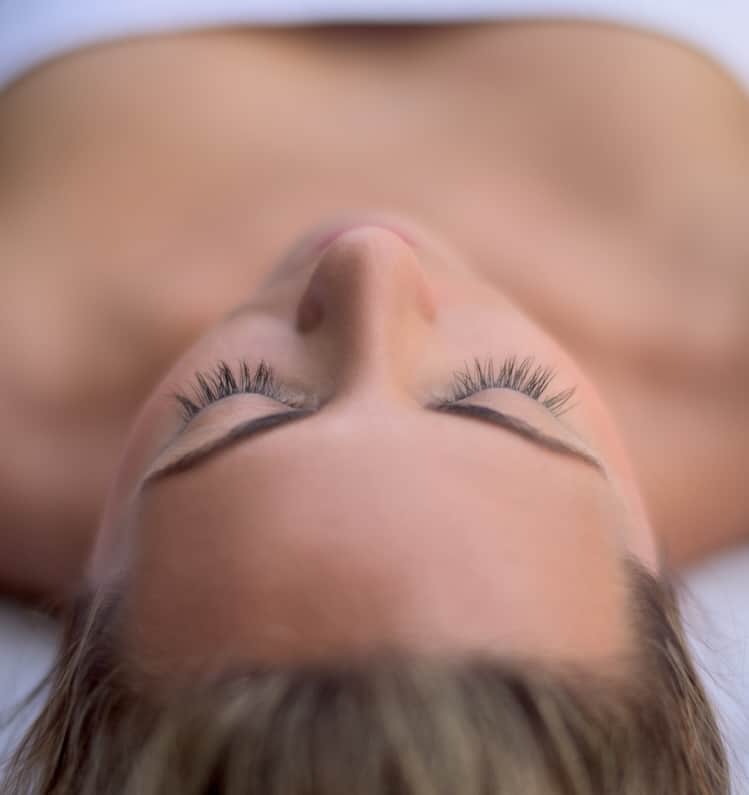 Young woman relaxing at the spa lying on the bed - beauty concepts